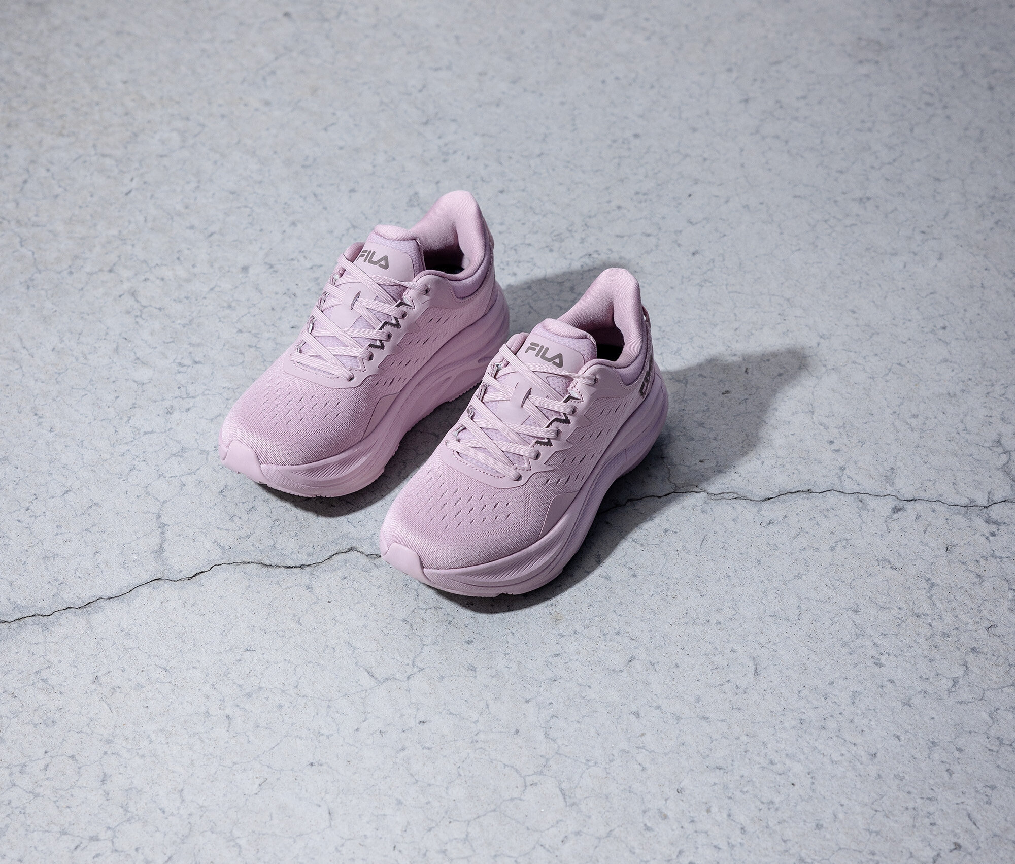 Dwa fioletowe buty do biegania Fila stoją na szarym tle.