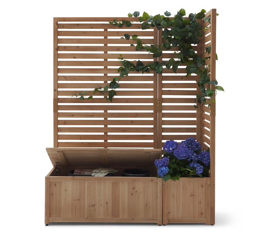 Drewniana konstrukcja z poziomymi listwami, częściowo porośnięta bluszczem. Pod spodem stoi drewniana skrzynia z otwartą pokrywą.