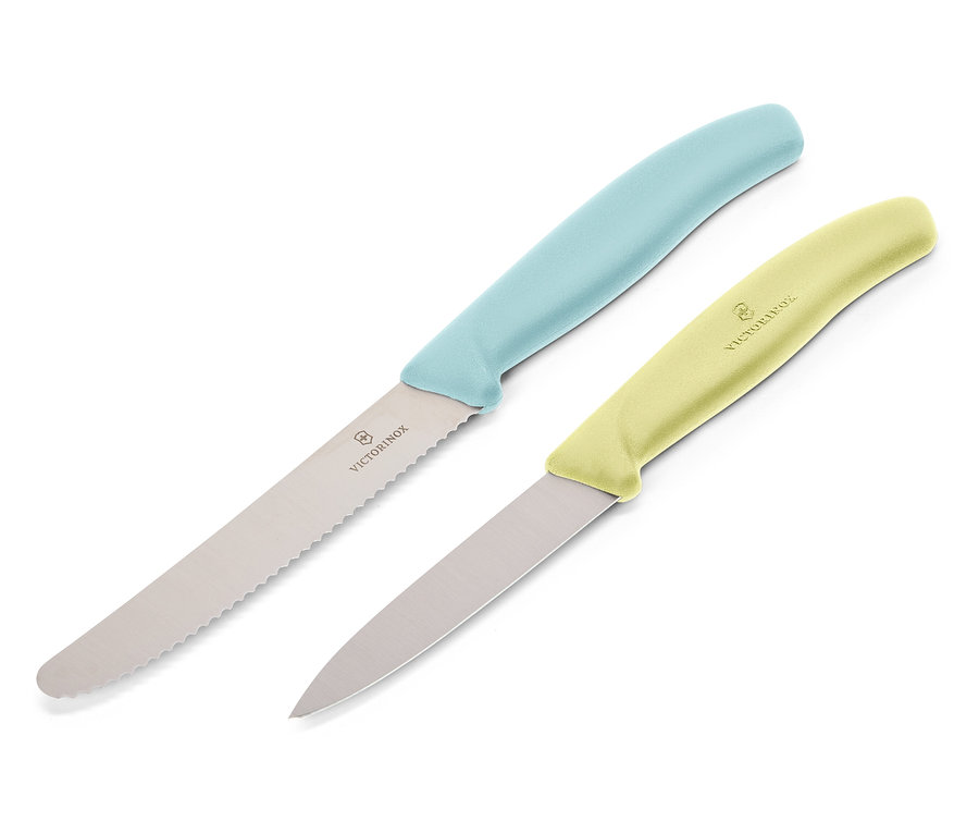Dwa noże Victorinox leżą ukośnie na białym tle. Górny nóż ma jasnoniebieską rękojeść i ząbkowane ostrze, dolny nóż ma jasnożółtą rękojeść i gładkie ostrze.