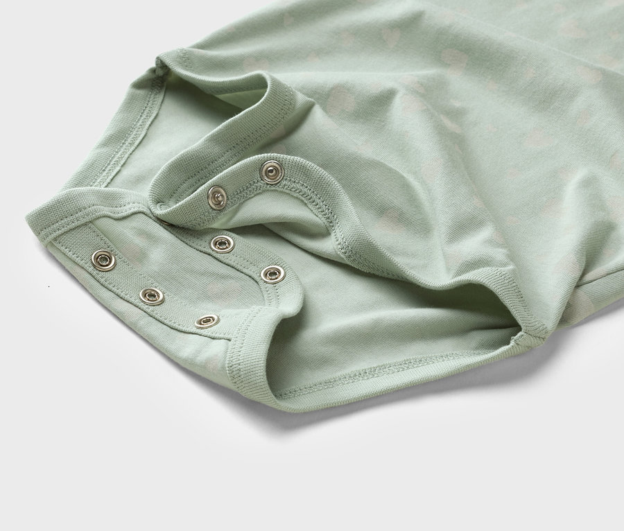 Zbliżenie jasnozielonego body dziecięcego z zatrzaskami.