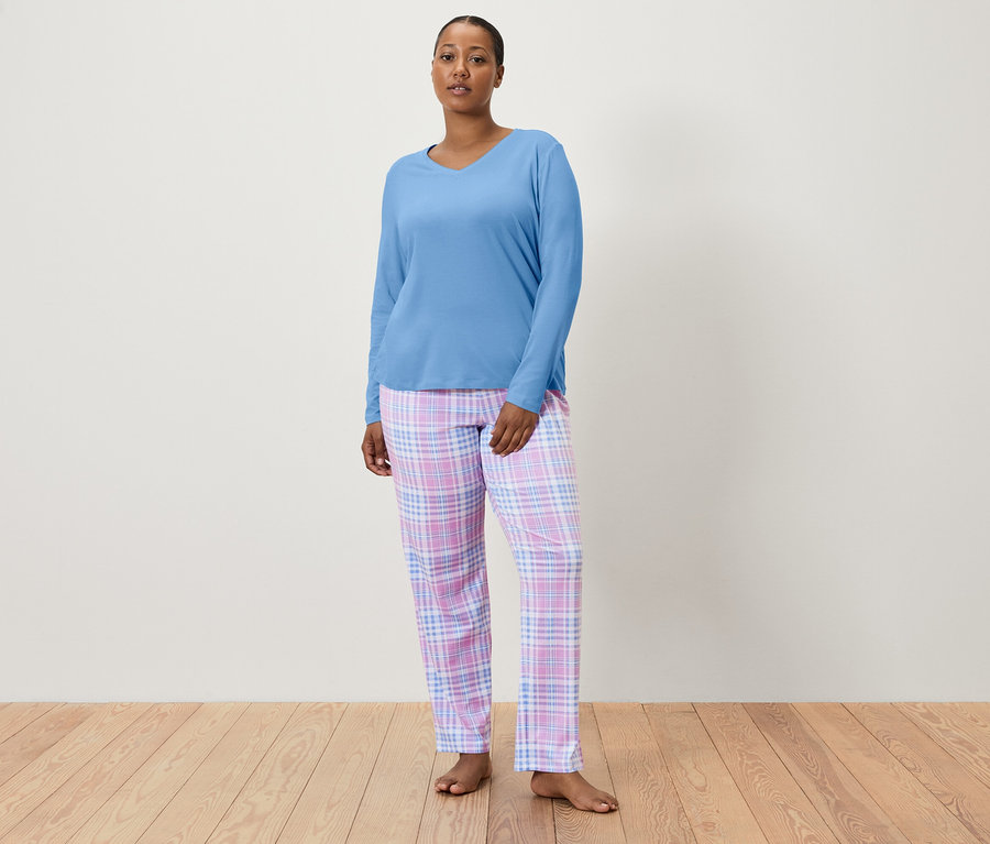 Kobieta ma na sobie niebieską górę od piżamy i spodnie od piżamy w kratę.