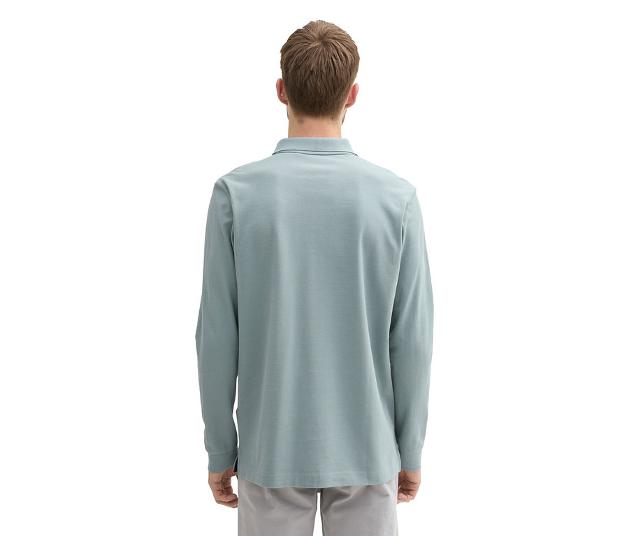 Mężczyzna od tyłu w koszulce polo z długim rękawem Tom Tailor z dzianiny pique, Grey Mint i szarych spodniach.