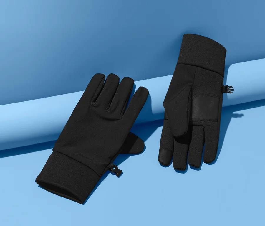 Dwie czarne rękawiczki softshell leżą na niebieskim tle.
