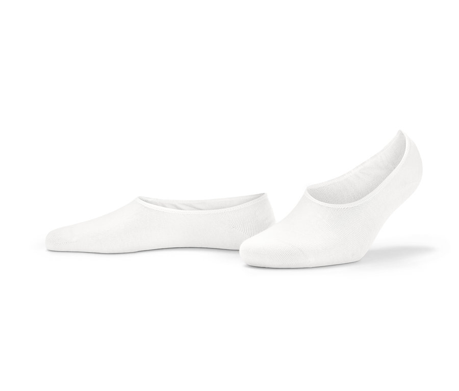 Dwie pary białych stopek do butów typu sneakers leżą na ziemi.