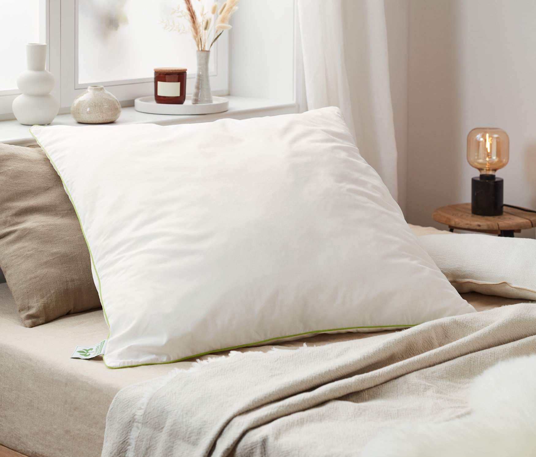 Na łóżku leżą poduszki z pierza irisette® greenline w różnych rozmiarach.