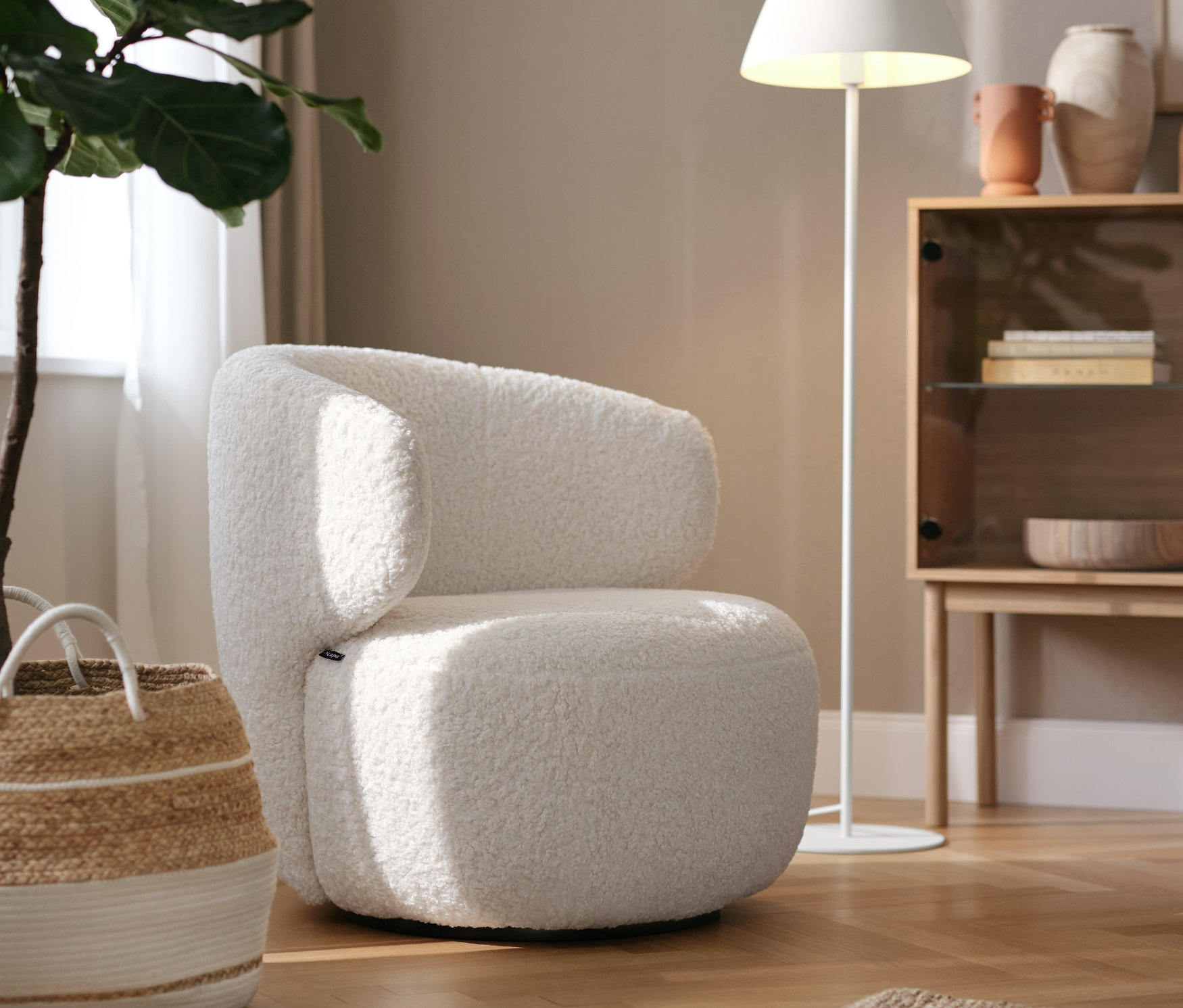 Biały fotel obrotowy stoi w salonie obok lampy.