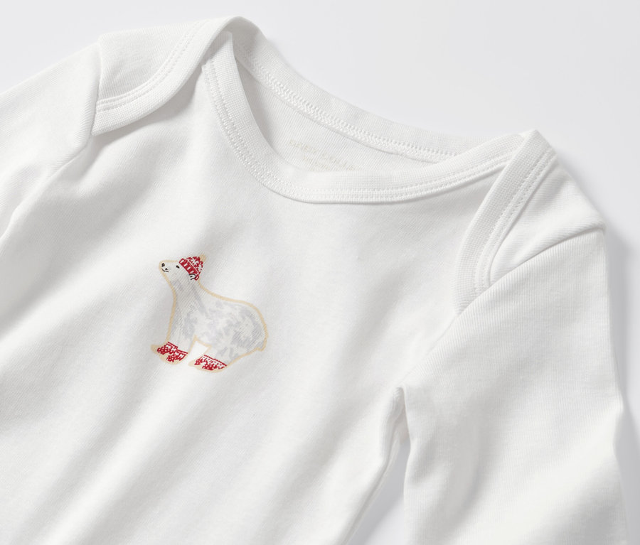 Zbliżenie na dziecięce body z długim rękawem, z motywem misia w czerwonej czapce i skarpetkach.