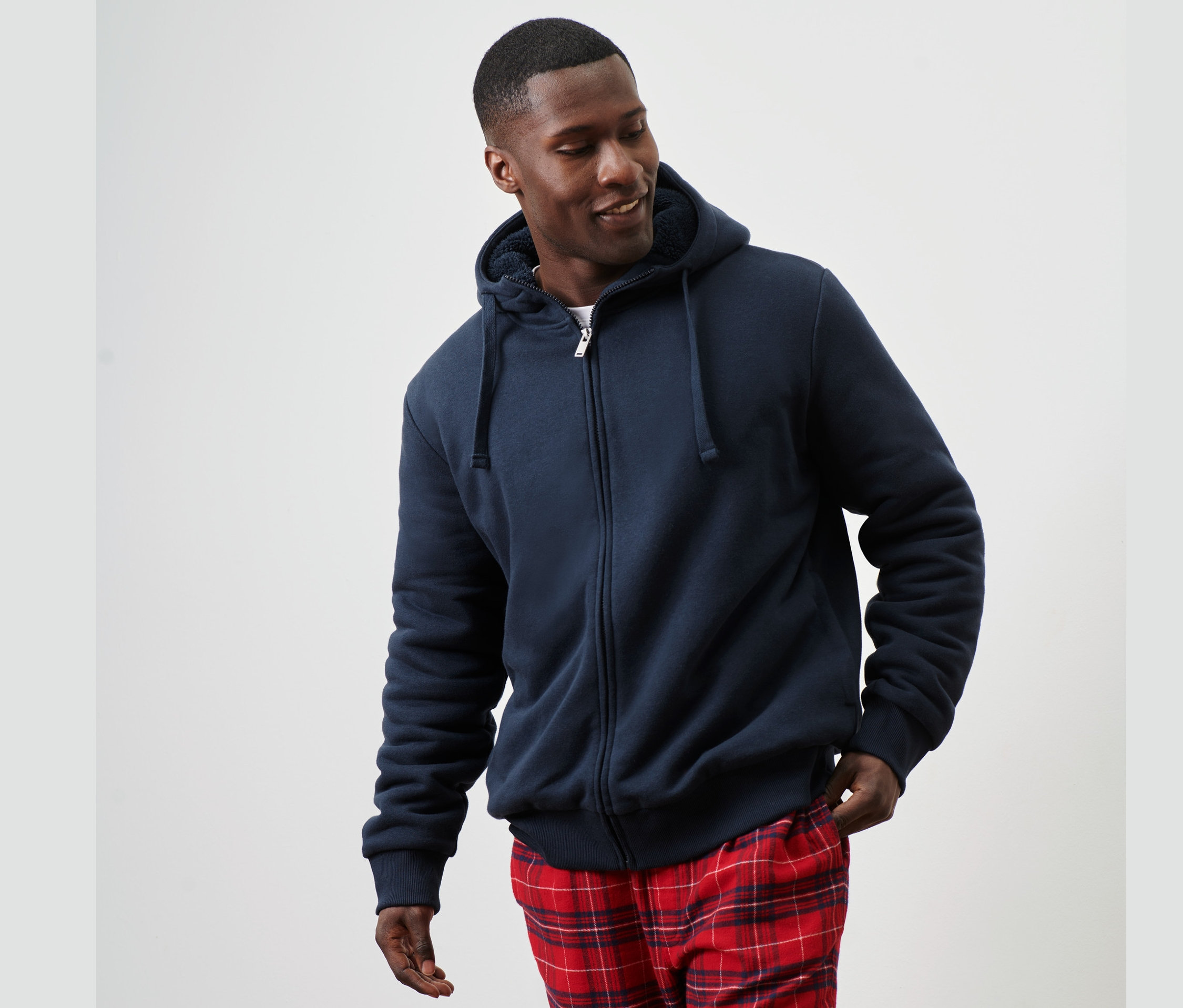 Mężczyzna ma na sobie bluzę dresową z kapturem na podszewce z pluszu i spodnie w kratę.