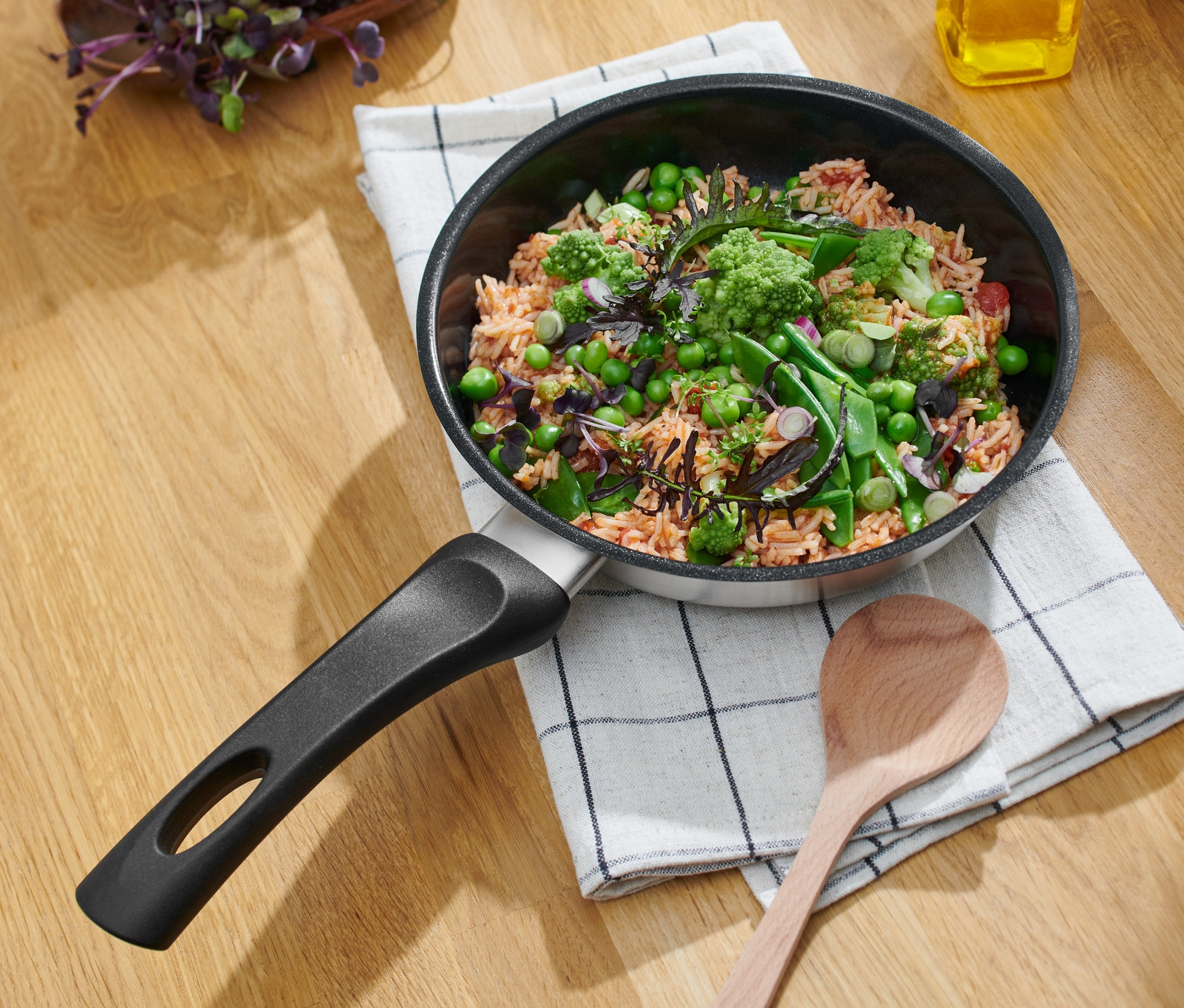 Patelnia ze stali nierdzewnej z powłoką ceramiczną o średnicy około 20 cm z jedzeniem na ściereczce w kratkę.