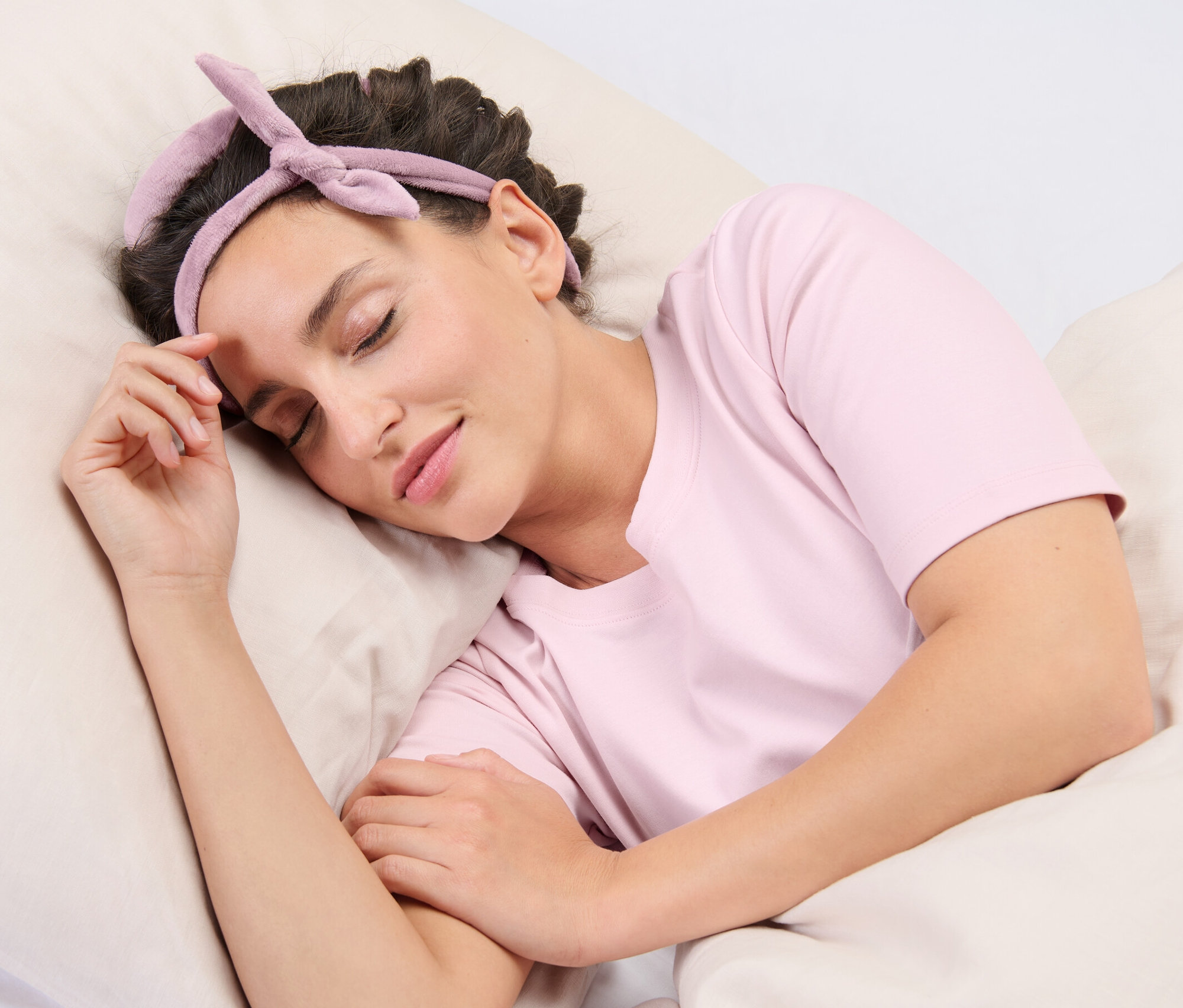 Kobieta śpi na poduszce, mając na włosach wałki do kręcenia włosów bez użycia ciepła.