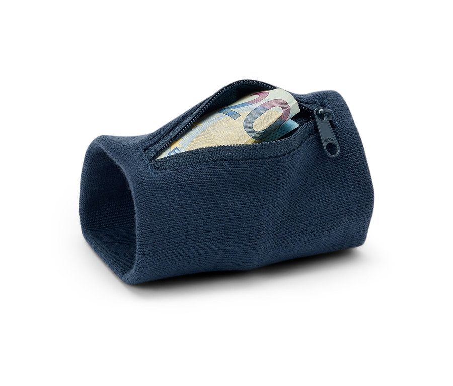 Zbliżenie granatowego antykradzieżowego portfela na nadgarstek z dwudziestoeurowym banknotem w środku, leżącego na białym tle.