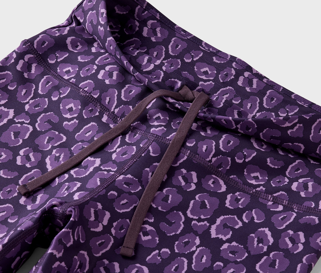 Zbliżenie na fioletowe legginsy we wzór zwierzęcy ze sznurkiem do ściągania w pasie.