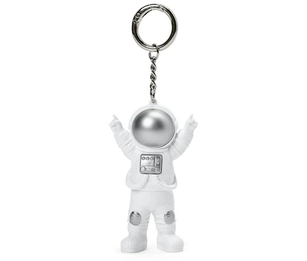 Biały brelok w kształcie astronauty z wyciągniętymi rękami.