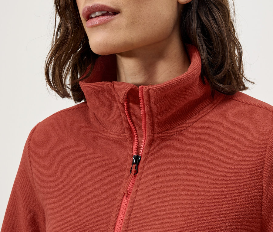 Zbliżenie damskiej bluzy polarowej ze stójką i zamkiem błyskawicznym.