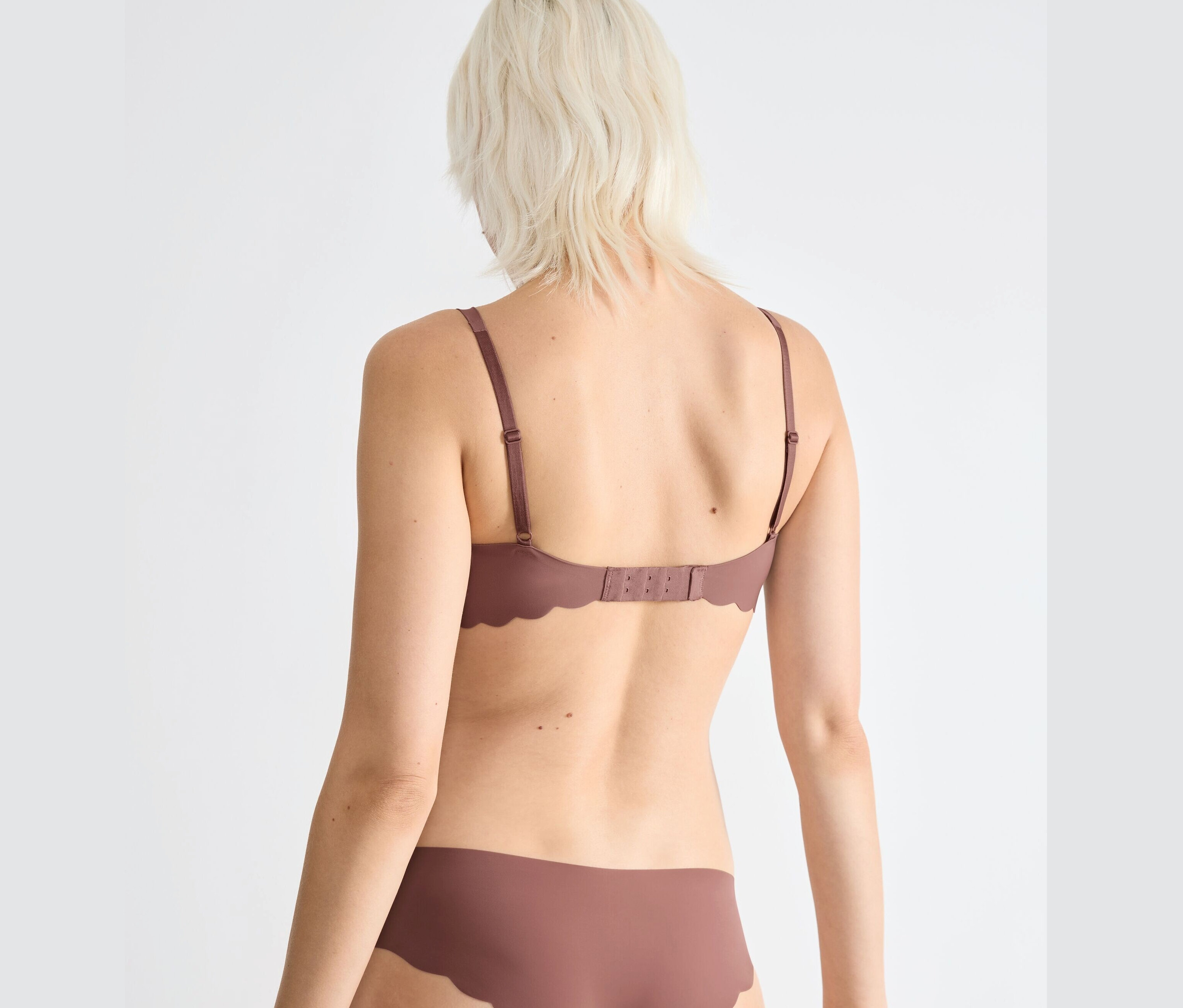 Widok z tyłu blondynki w brązowym miękkim biustonoszu sloggi ZERO Microfibre 2.0 i majtkach.