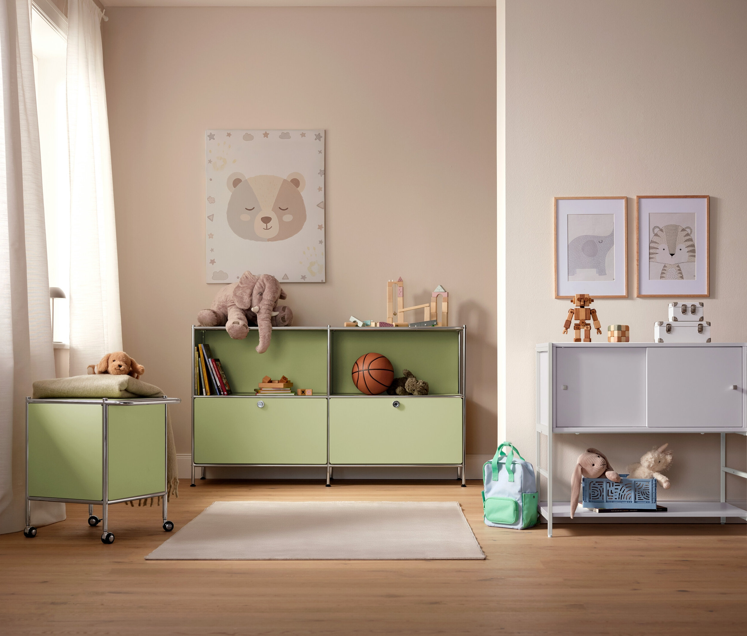 Pokój dziecięcy z jasnozielonymi i białymi szafkami, zabawkami i obrazkami na ścianie.