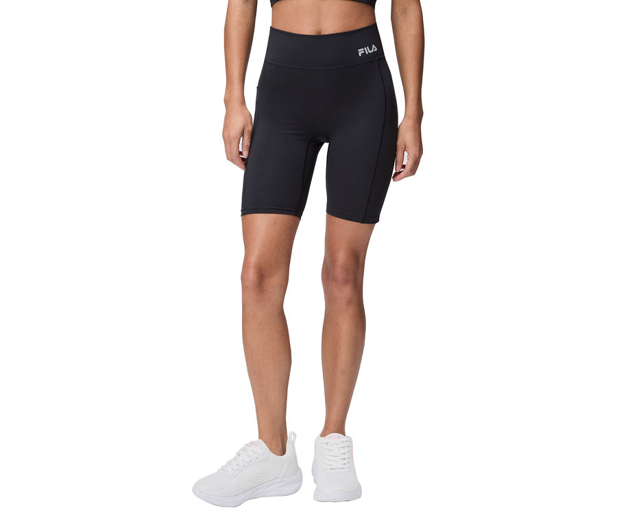 Kobieta ma na sobie czarne spodenki rowerowe Fila i białe tenisówki.
