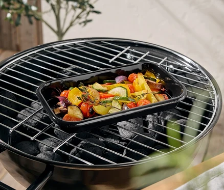 Warzywa w czarnym naczyniu żaroodpornym na grillu.
