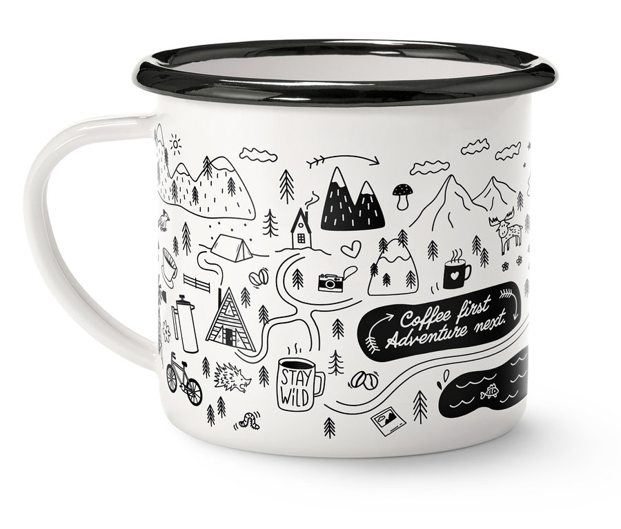 Biały kubek z czarnym brzegiem i uchwytem, ozdobiony rysunkiem gór, drzew i napisem "Coffee first, Adventure next".