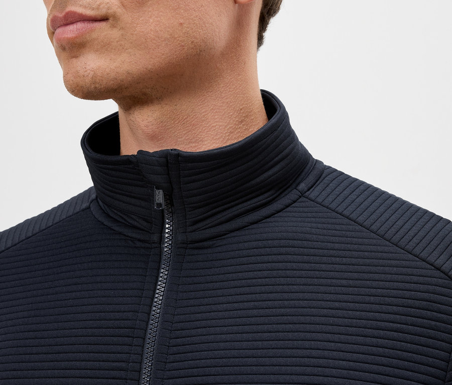 Zbliżenie mężczyzny w granatowej kurtce zapinanej na zamek z golfem.