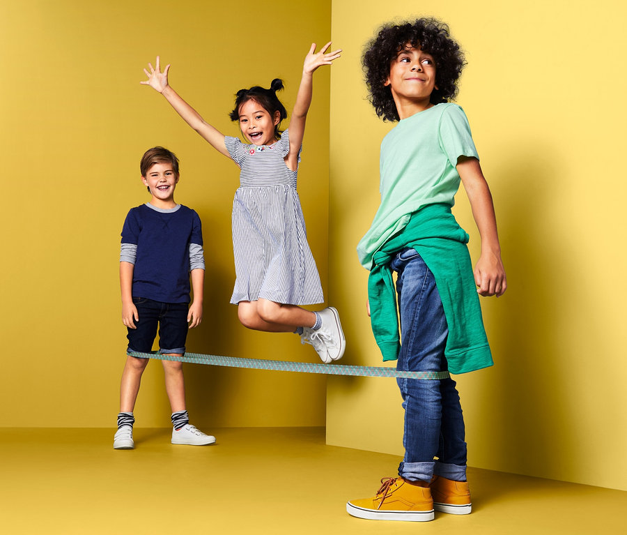 Troje dzieci bawi się szeroką gumą do skakania z woreczkiem do przechowywania.