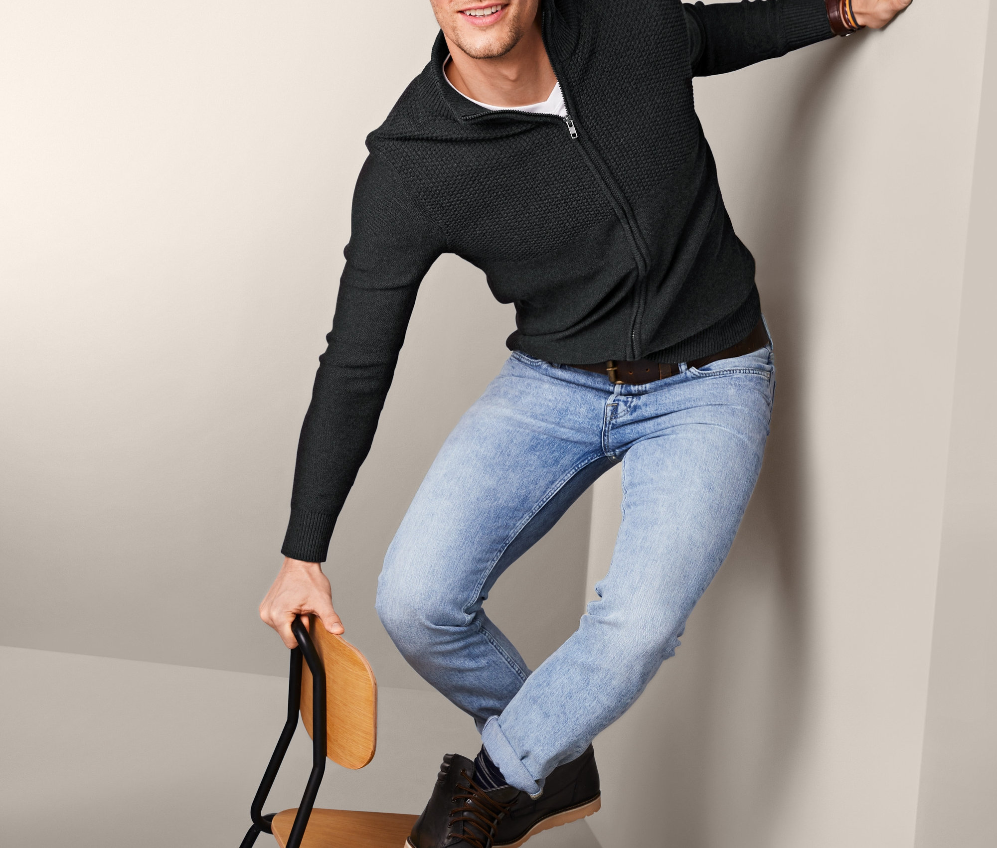 Mężczyzna stoi na krześle, ubrany w bluzę męską z dzianiny z bawełną ekologiczną.