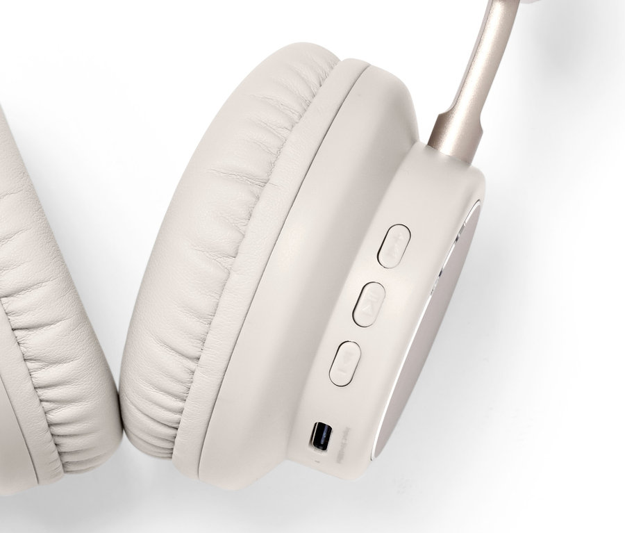 Szczegółowy widok jasno-beżowych słuchawek nausznych Bluetooth® na białym tle.