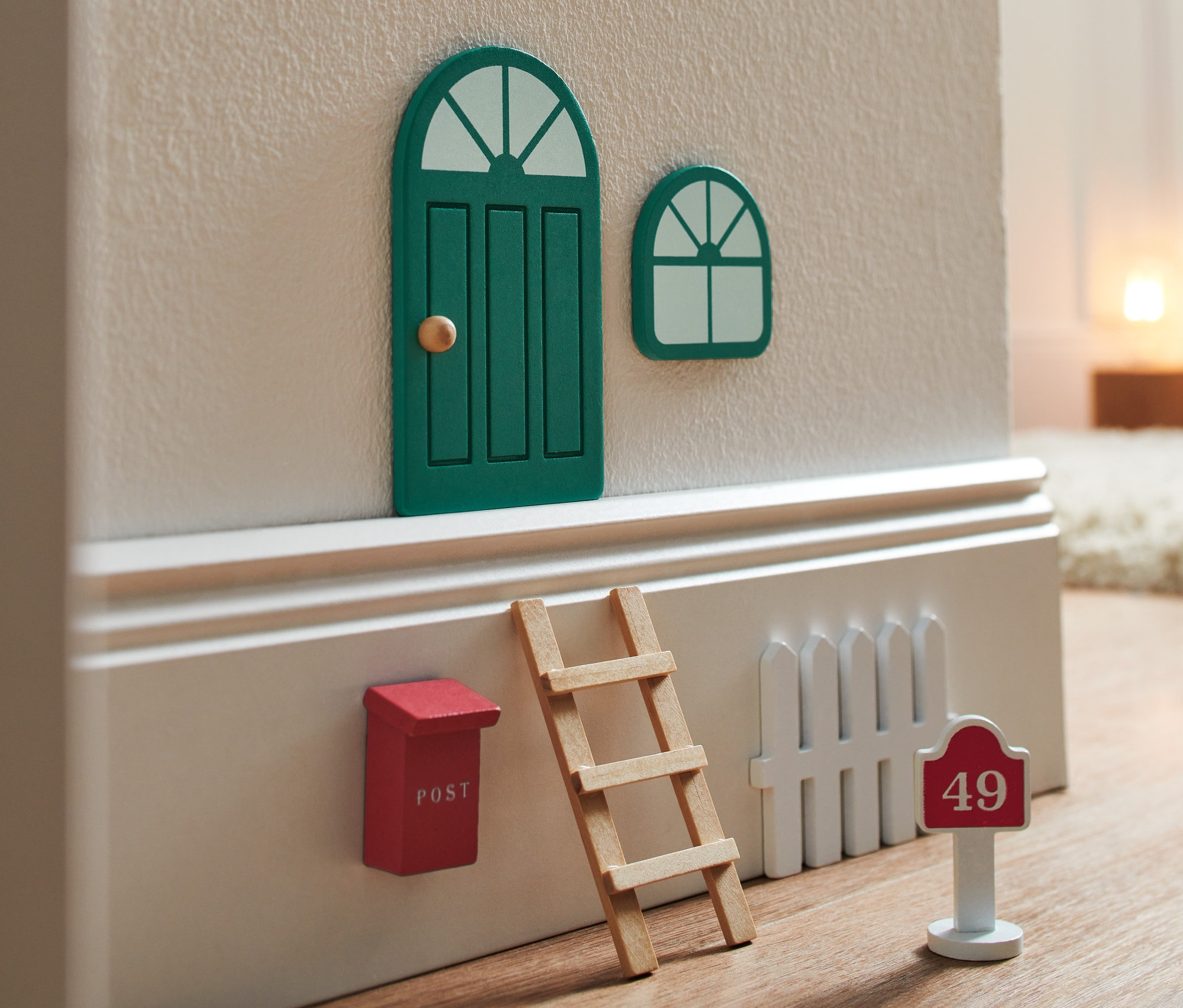 Zestaw "domek dla krasnoludka" ze zamkniętymi zielonymi drzwiami i oknem, czerwoną skrzynką pocztową, drabinką i białym płotem z numerem domu 49.