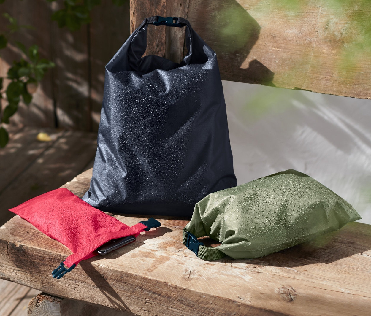 Na drewnianej ławce leżą trzy wodoodporne worki.