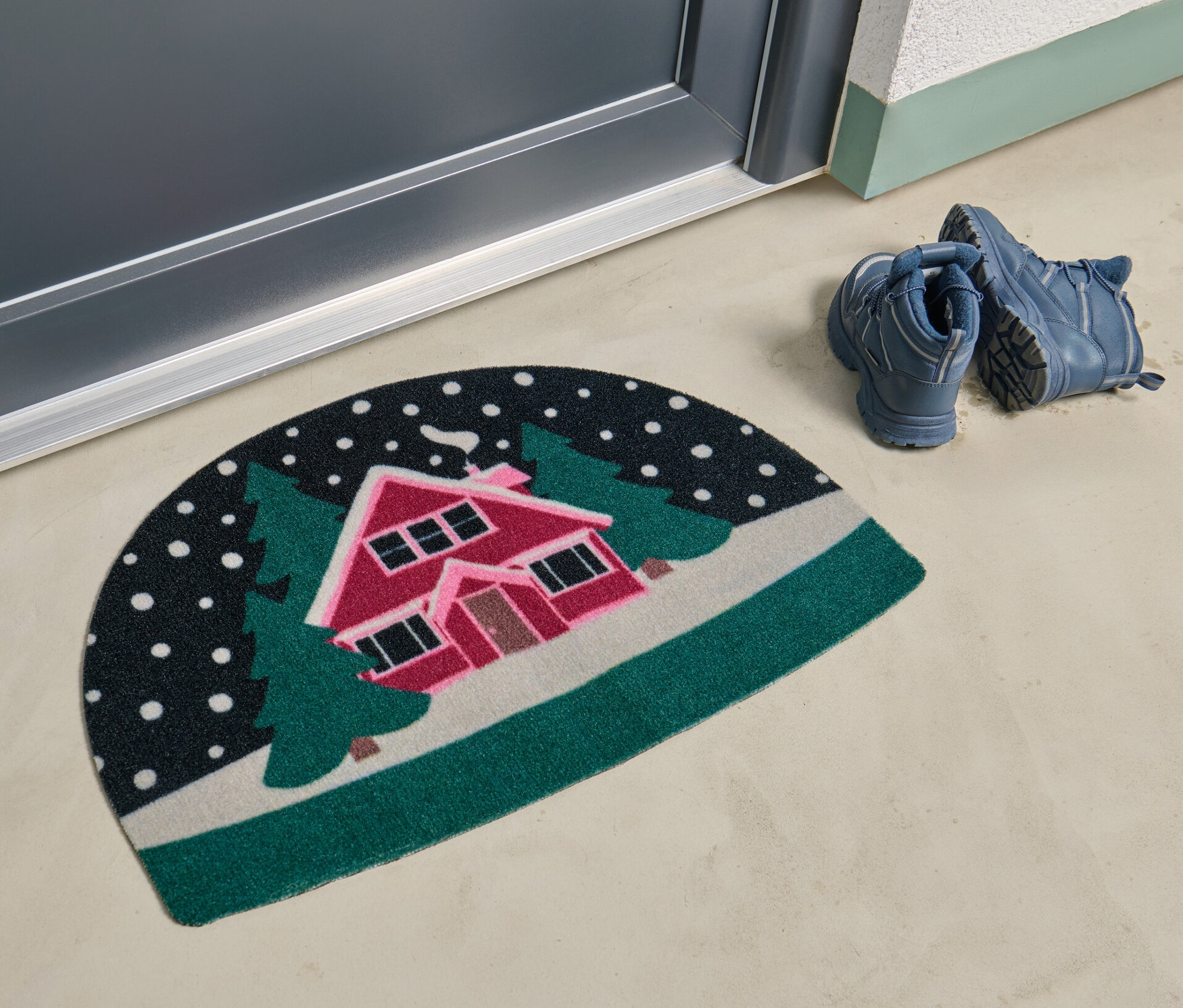 Wycieraczka z motywem zaśnieżonego krajobrazu leży przed drzwiami.