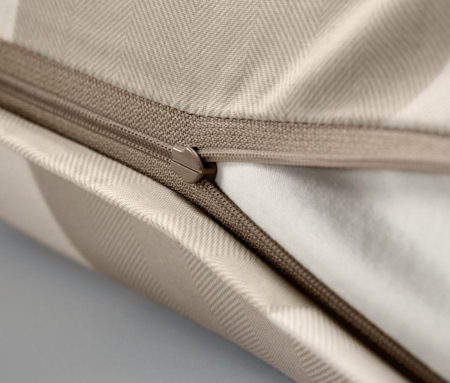 Zbliżenie beżowej poszewki na poduszkę z zamkiem błyskawicznym.