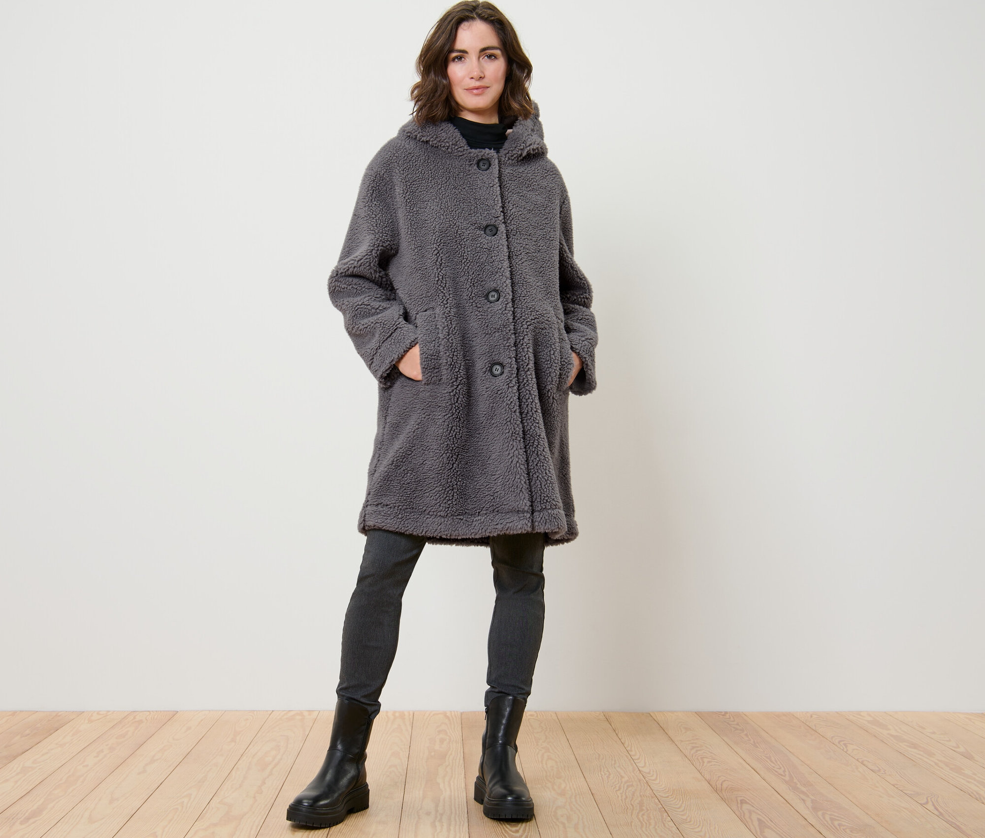 Kobieta pozuje w pluszowym płaszczu z kapturem.