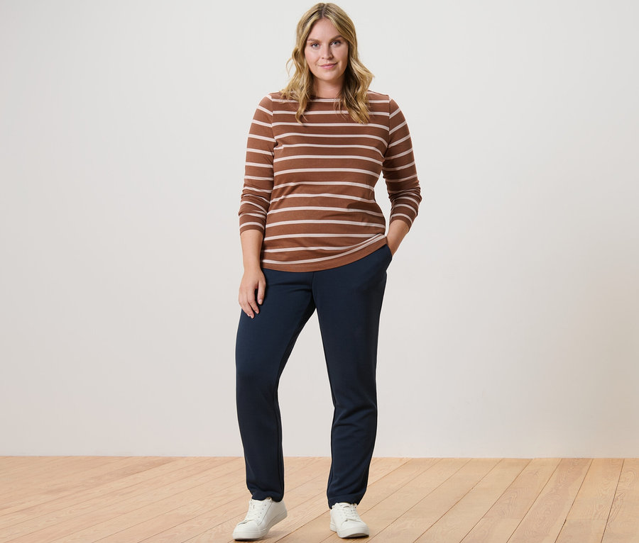 Kobieta pozuje w pasiasta koszulka z długimi rękawami, koniakowa i spodnie dresowe.