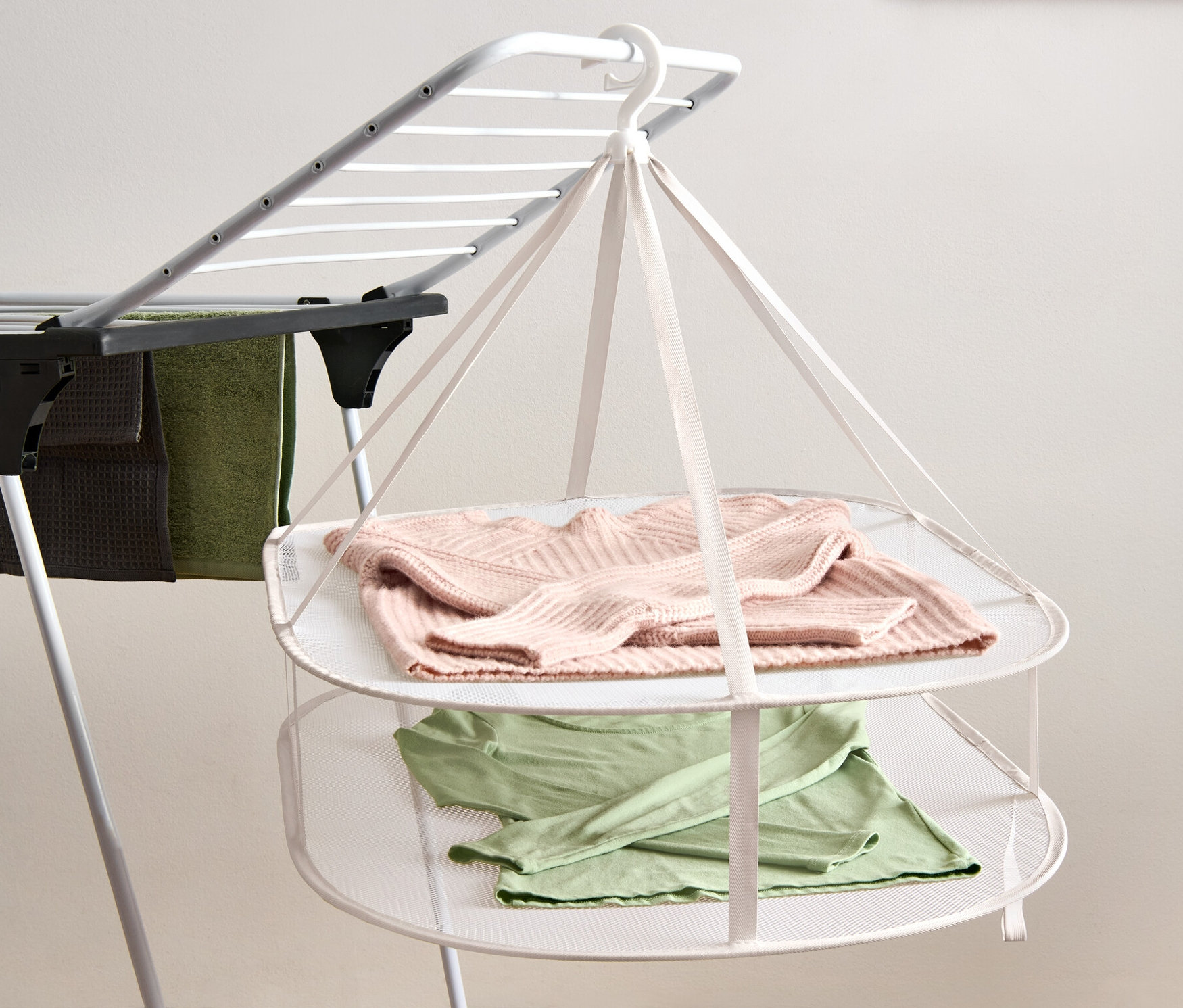 Na suszarce wiszą różowy sweter i zielona koszulka.