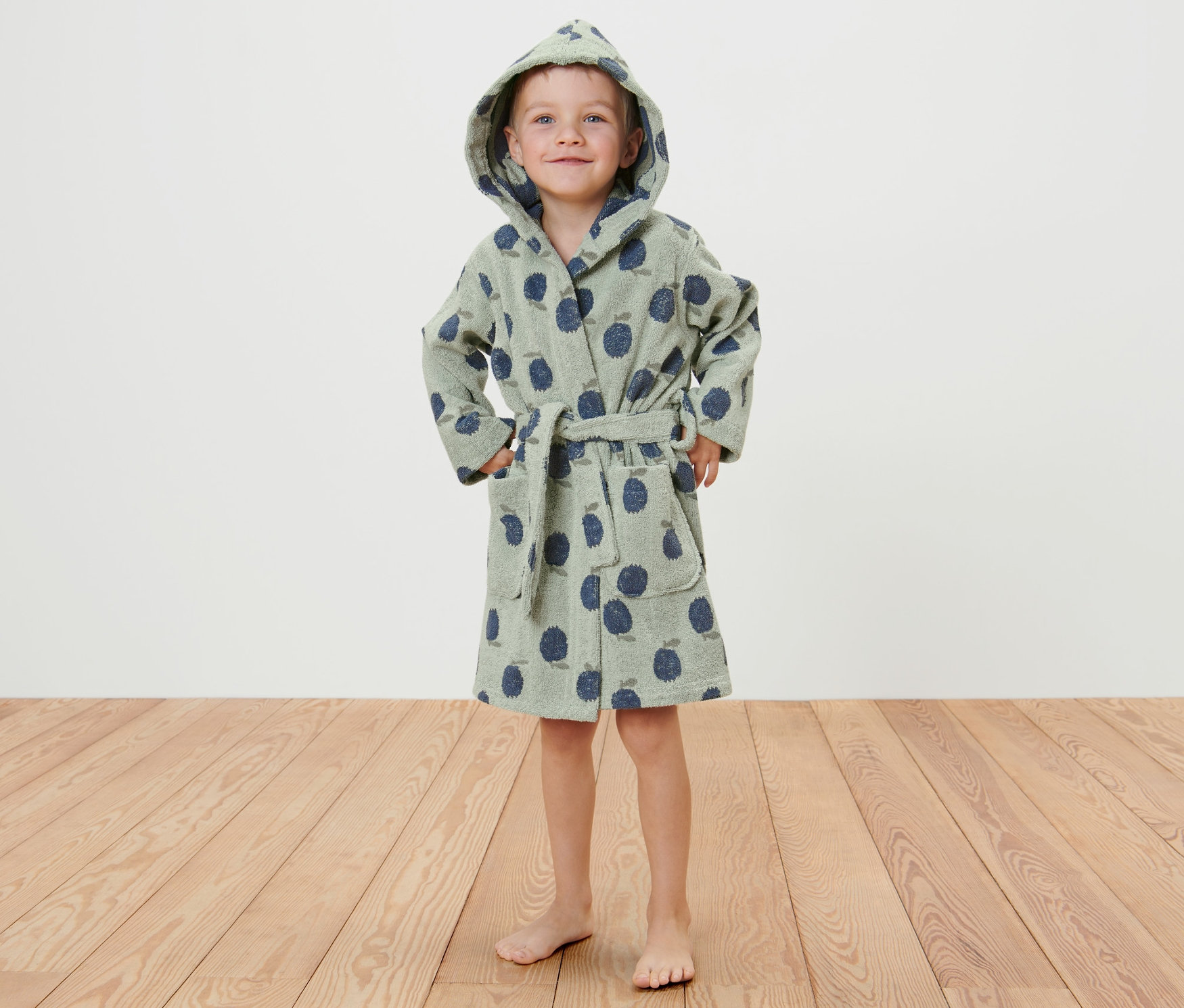 Chłopiec stoi w szlafroku dziecięcym.