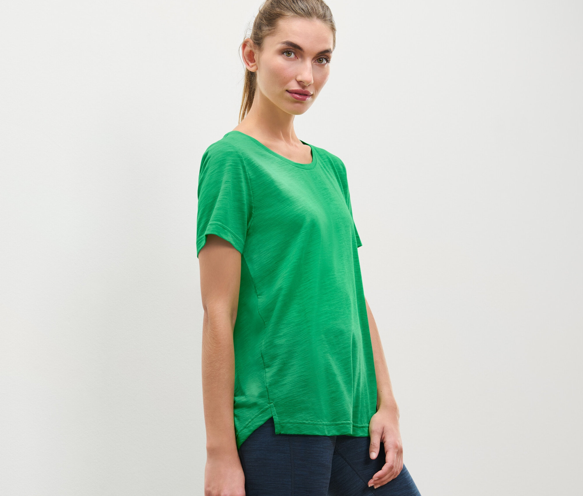 Kobieta pozuje w koszulce sportowej.