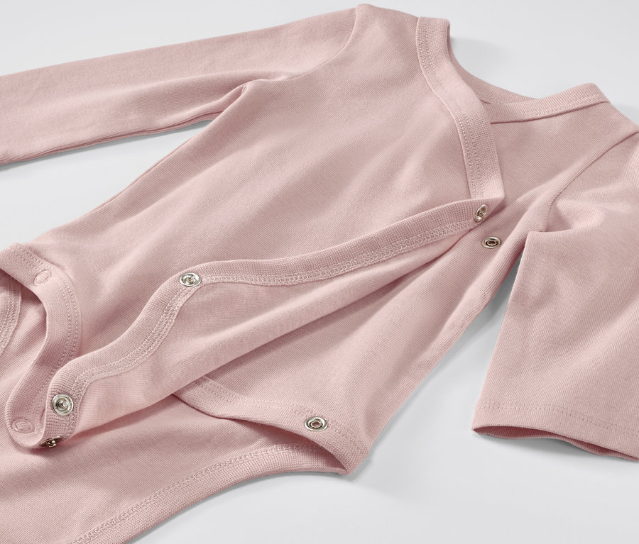 Zbliżenie na różowe body niemowlęce z długim rękawem, zapinane na zatrzaski.