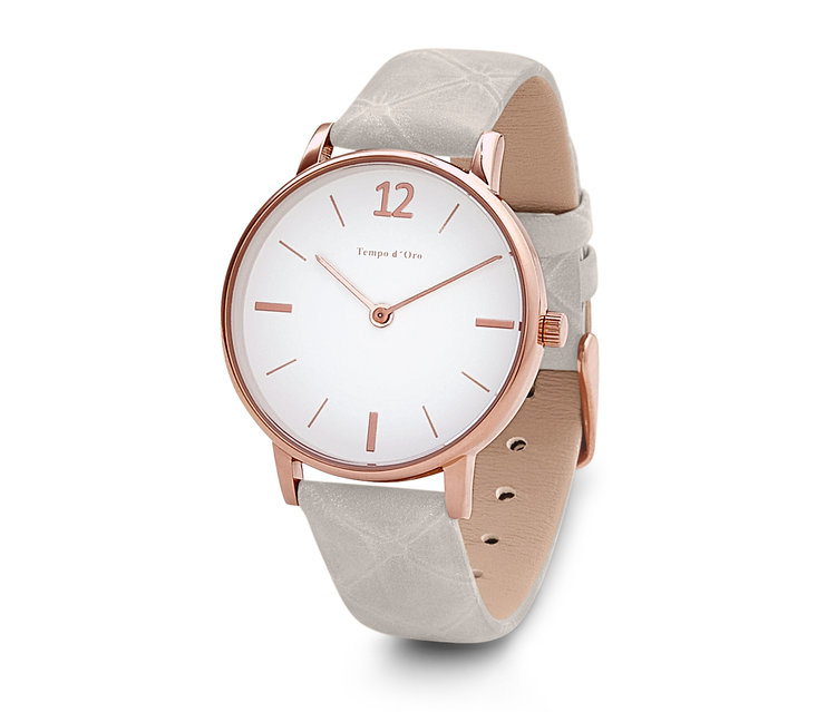 Zbliżenie zegarka na rękę ze skórzanym paskiem, białą tarczą i kopertą z różowego złota.