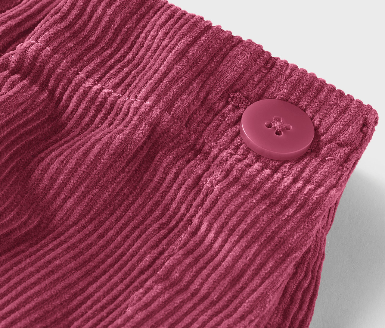 Zbliżenie bordowej tkaniny sztruksowej z guzikiem.