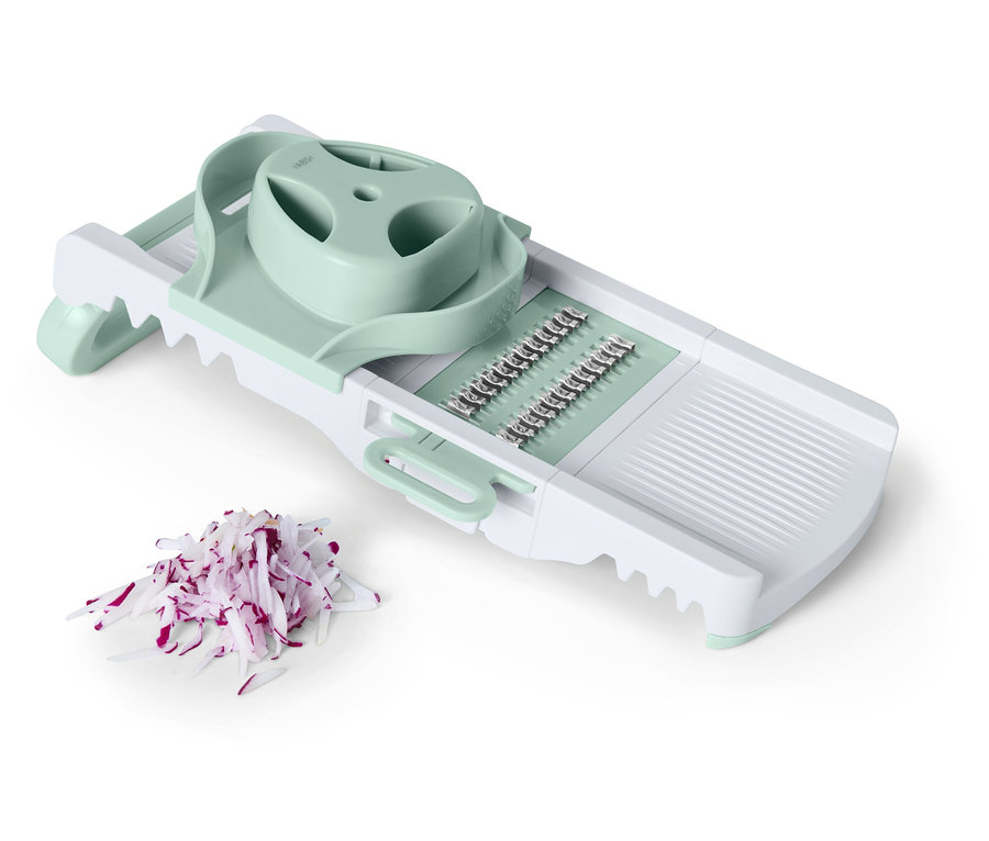 Biała krajalnica do warzyw z jasnozielonymi akcentami obok pokrojonej czerwonej cebuli.