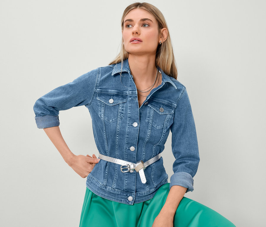 Blondynka pozuje w kurtce dżinsowej i spódnicy z satyny.