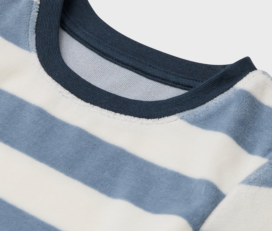 Szczegół niebiesko-białej koszulki w paski z granatowym dekoltem.