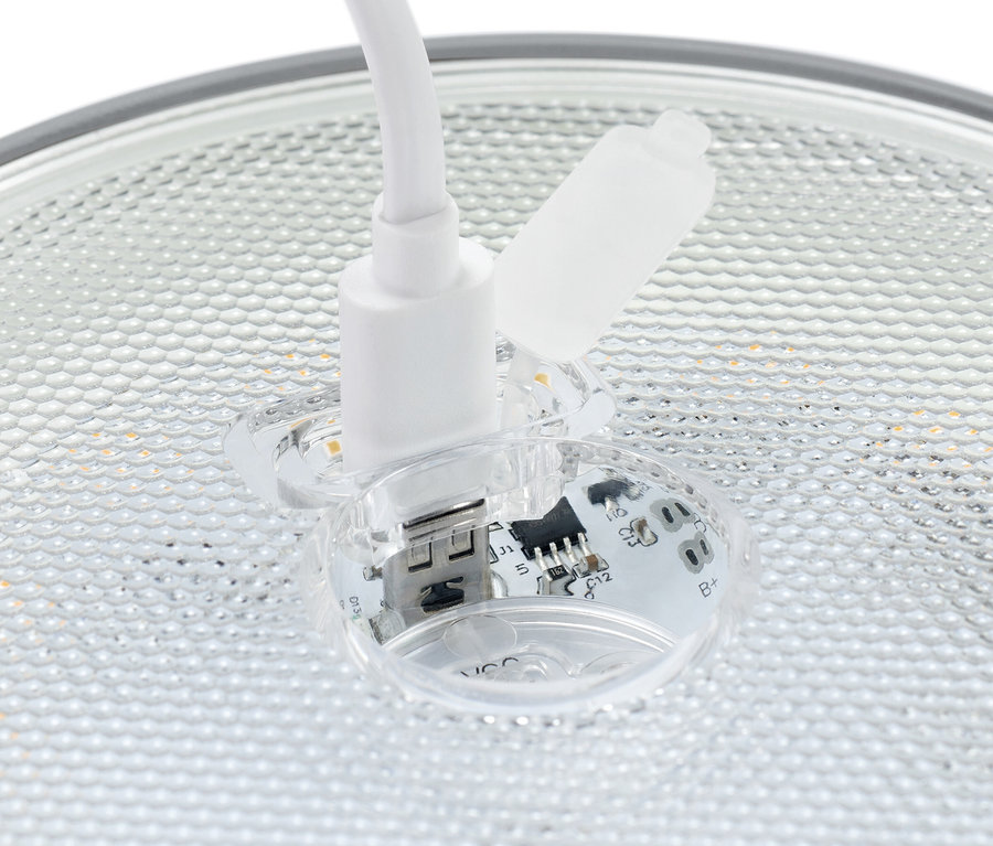 Zbliżenie białej wtyczki USB włożonej do przezroczystego gniazda z widocznymi elementami elektronicznymi.