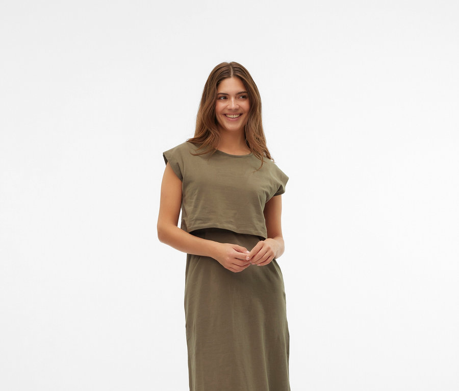 Kobieta ma na sobie sukienkę w kolorze khaki i kremowe buty Mary Jane na białym tle.