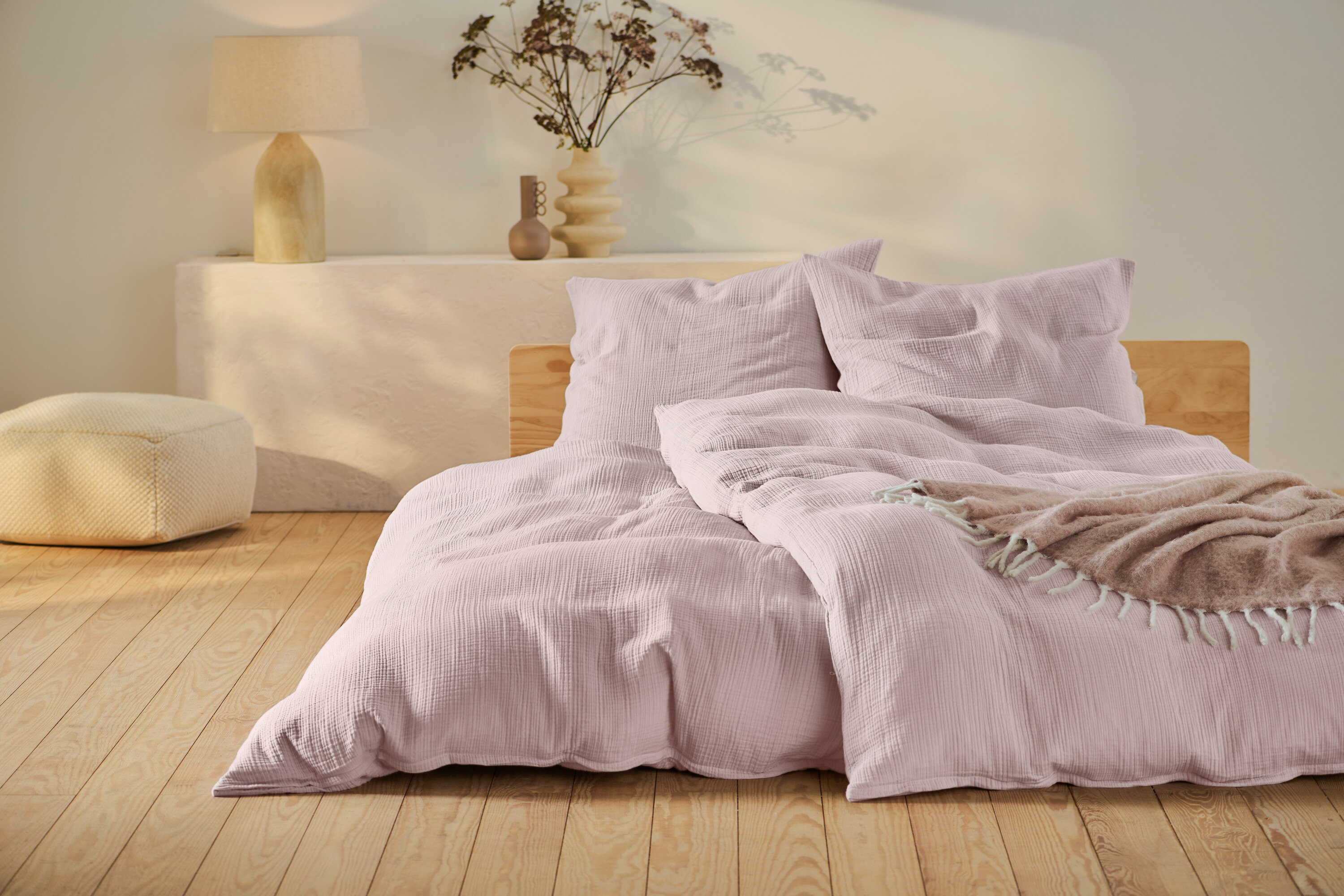 Różowa pościel muślinowa w standardowym i niestandardowym rozmiarze na łóżku z drewnianą ramą.