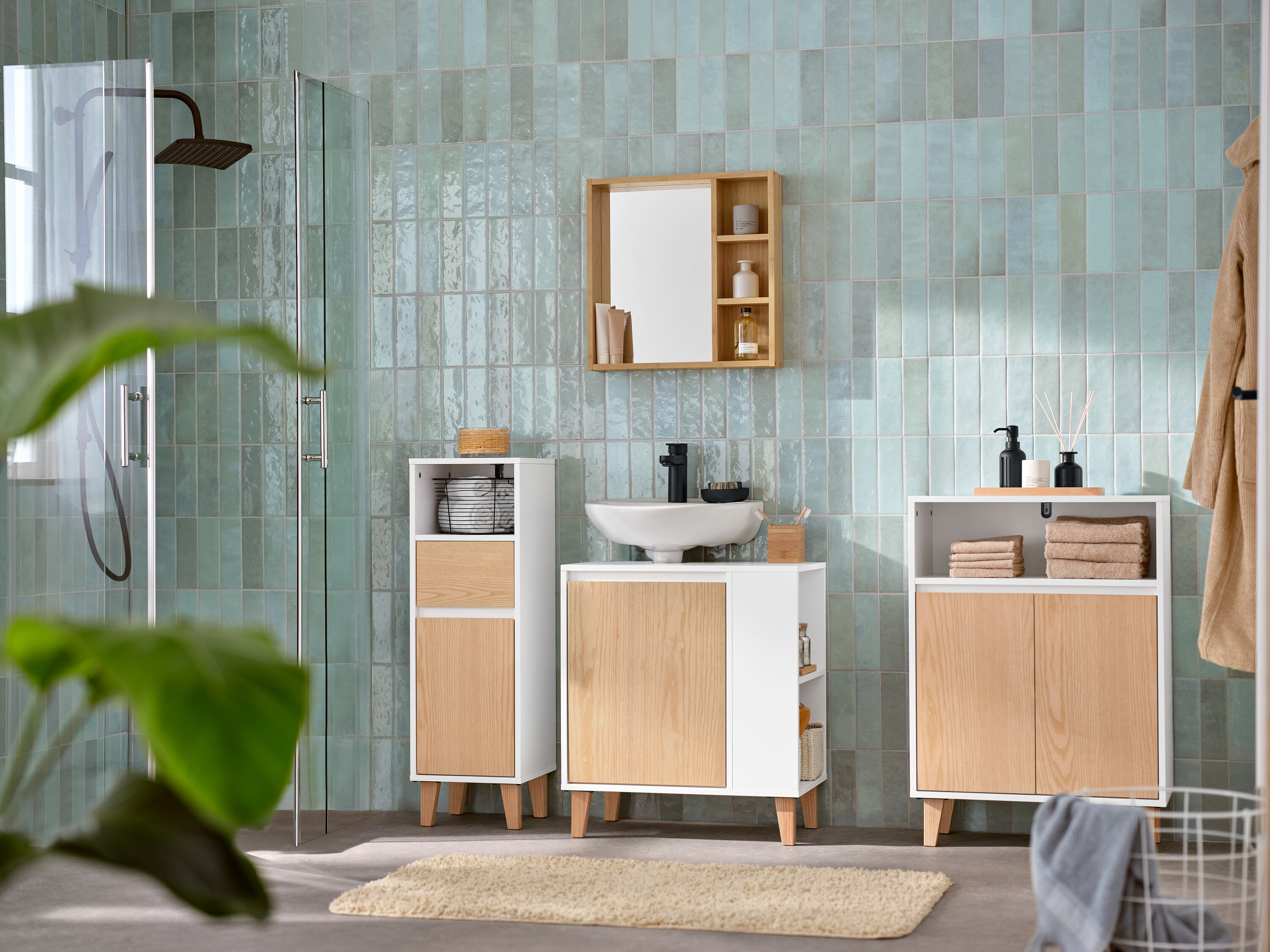 Łazienka z szafką pod umywalkę z boczną przegródką, lustrem z półkami, szafką łazienkową i wąską szafką łazienkową.