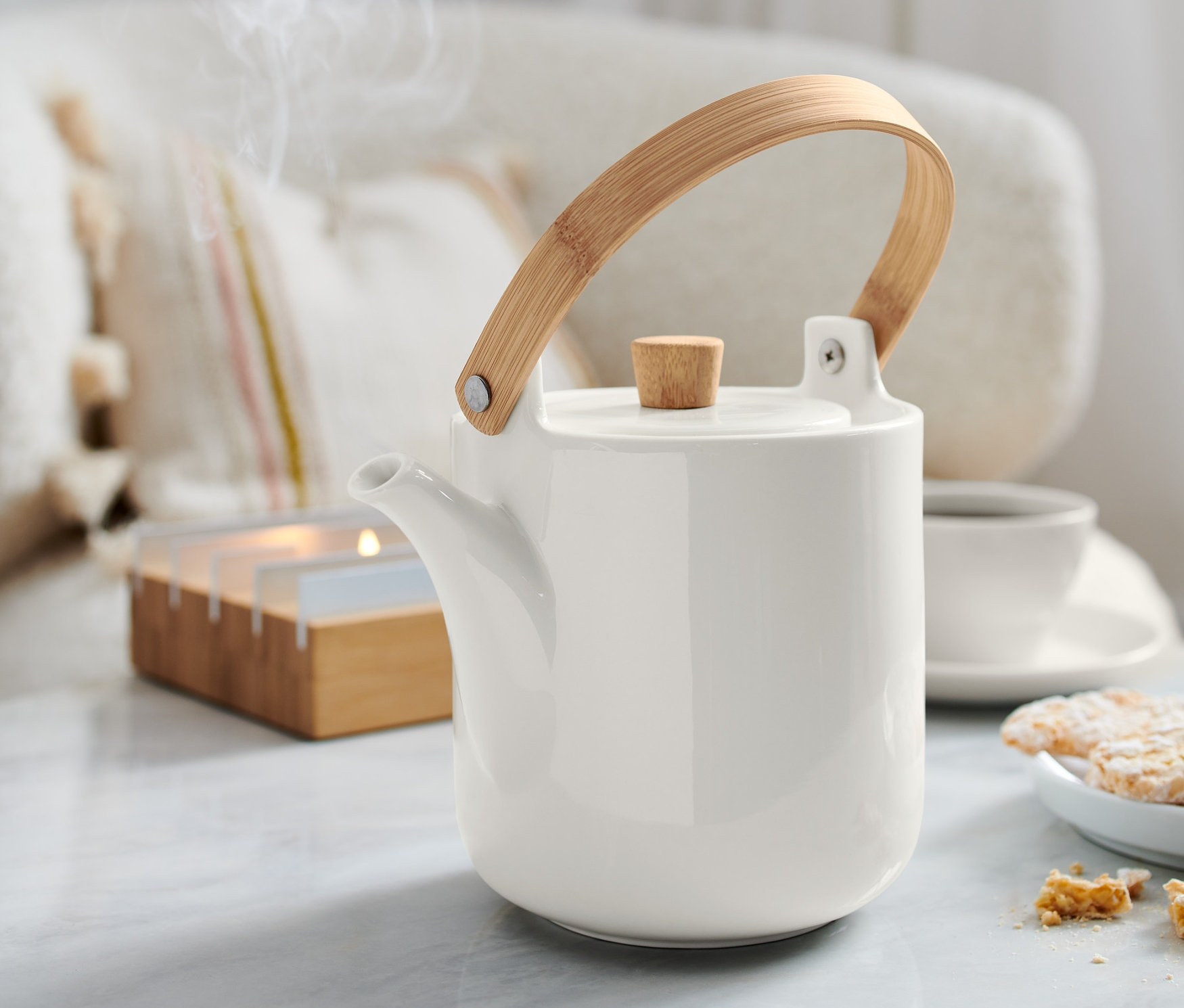 Dzbanek do herbaty stoi na stole. Z dzbanka unosi się para.