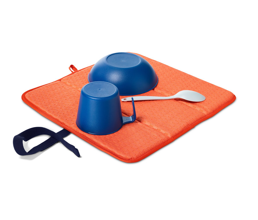 Niebieska miska, kubek i łyżka na pomarańczowej składanej macie-ociekaczu.