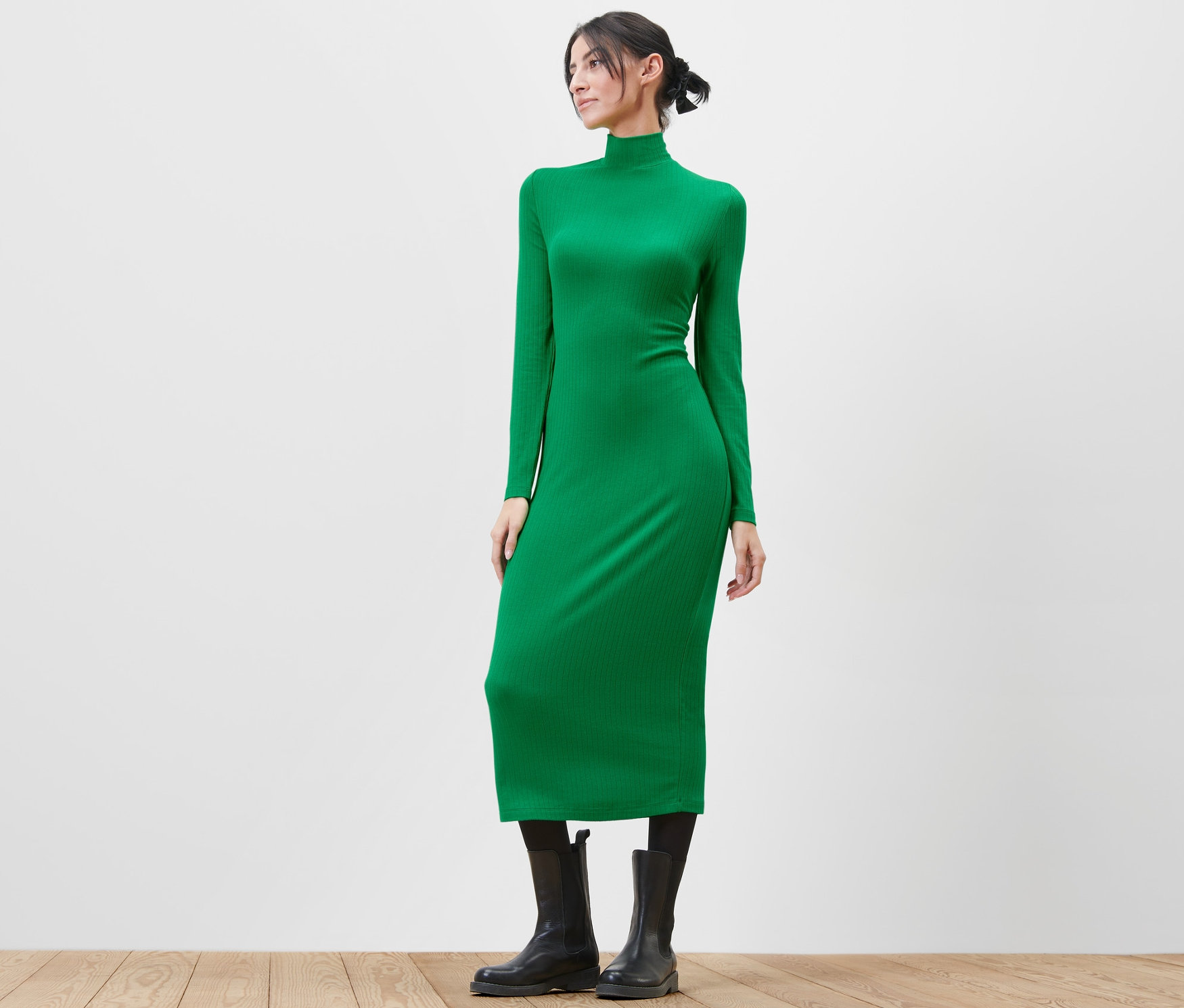 Kobieta pozuje w zielonej sukience dżersejowej.