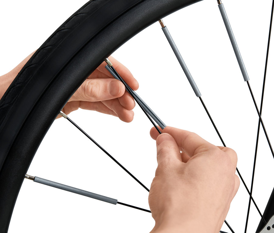 Osoba montuje 36 odblasków na szprychy roweru.